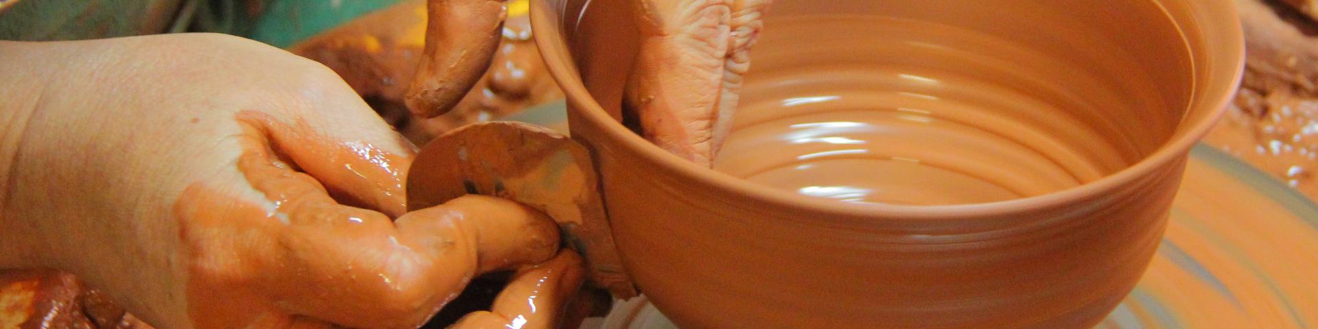 Mains d’un potier façonnant un bol en argile sur un tour de poterie à l'atelier Hostein Noe à Aubagne