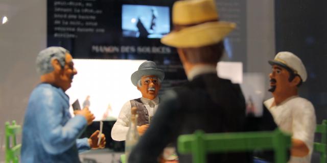 Santons représentant une scène provençale en discussion dans une exposition muséale au Petit Monde à Aubagne