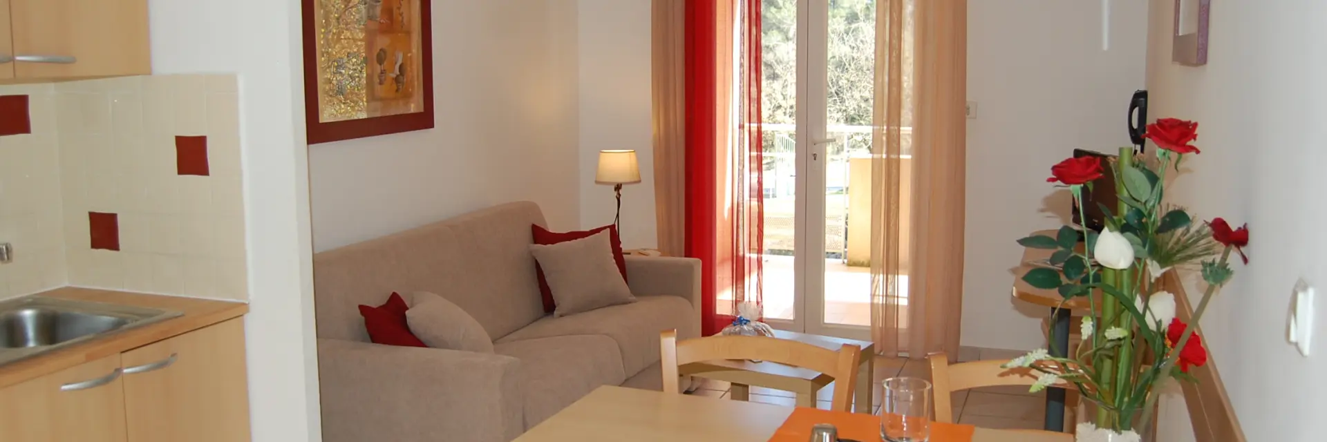 Séjour lumineux avec table à manger, cuisine ouverte, canapé, décoration moderne et porte-fenêtre donnant sur l’extérieur. Hébergement de résidence de tourisme à Peypin