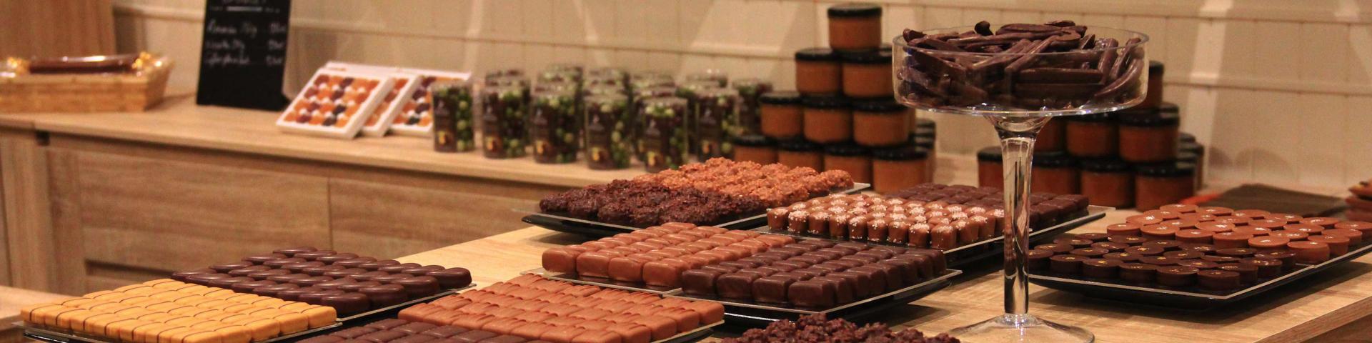 Table en bois présentant des plateaux de chocolats et confiseries artisanales dans une boutique à l’ambiance chaleureuse à la Biscuiterie et salon de thé chez Clément et Olivier