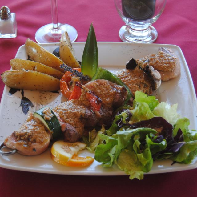 Assiette de viande grillée accompagnée de pommes de terre rôties, légumes grillés et salade verte, servie sur une table de restaurant à Aubagne